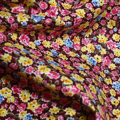Popeline de Coton motif champs de fleurs sur fond bordeaux vendu au coupon