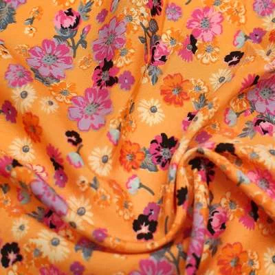 Tissu crêpe polyester imprimé fleurs sauvages fond orange vendu au coupon