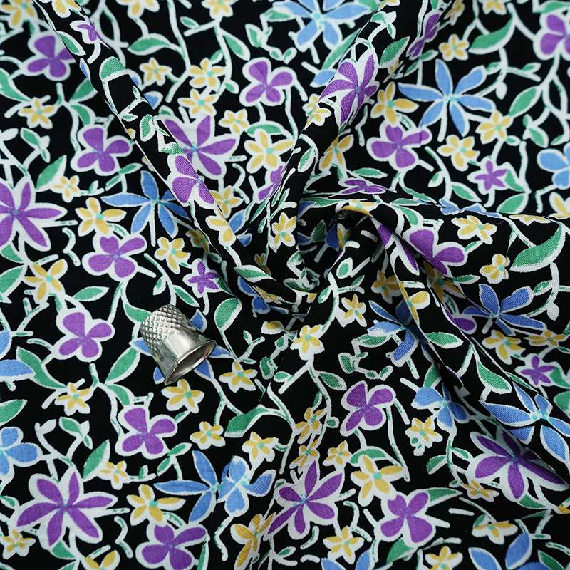 Tissu fibranne viscose noir étalé avec des motifs floraux distincts