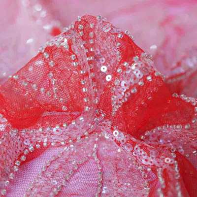 Tissu en dentelle rose et rouge à paillettes sous la lumière