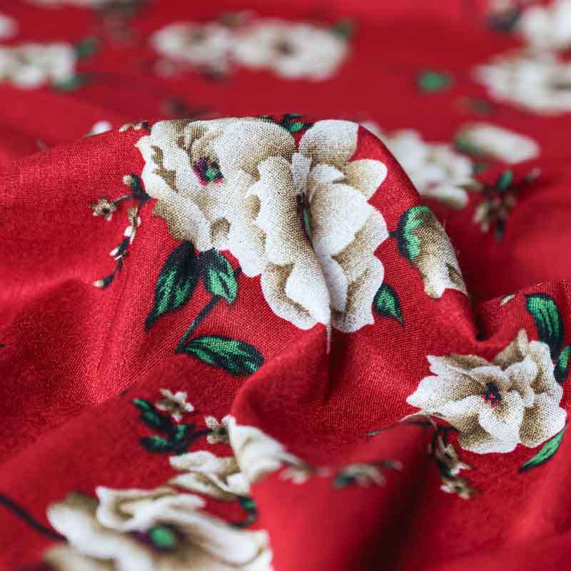 Tissu fibranne viscose à motif floral beige sur fond bordeaux.