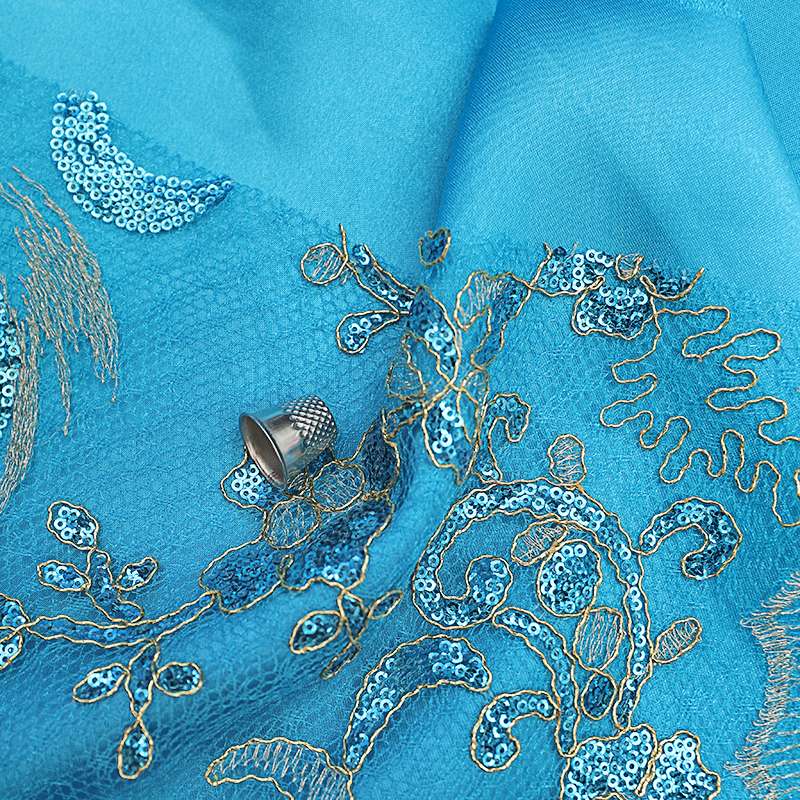 Tissu organza turquoise avec paillettes et fil doré, idéal pour des robes de mariée et des costumes de gala raffinés.